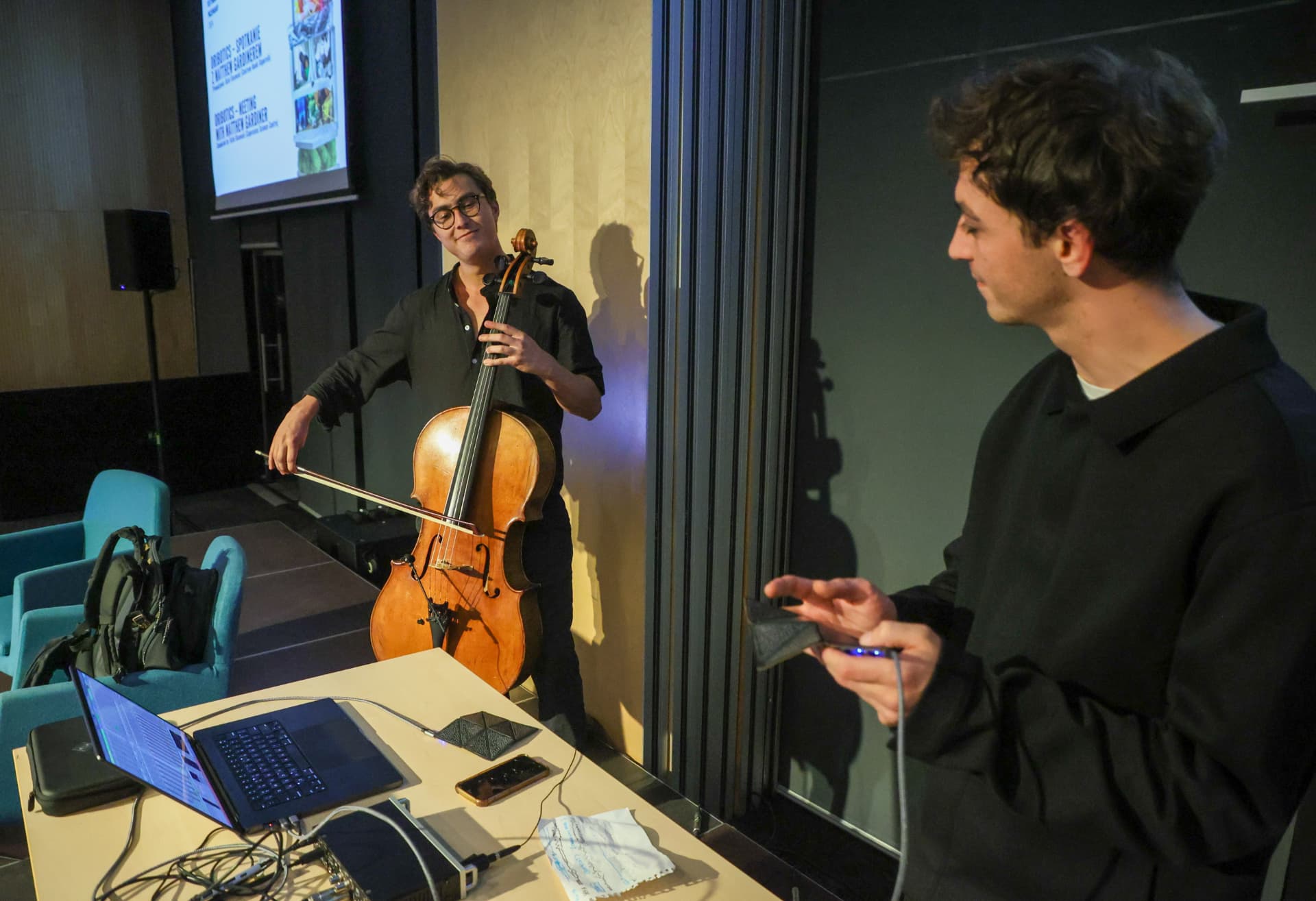 Cellist bowing while an electronic performer gestures over a sensor at Festiwal Przemiany 2024